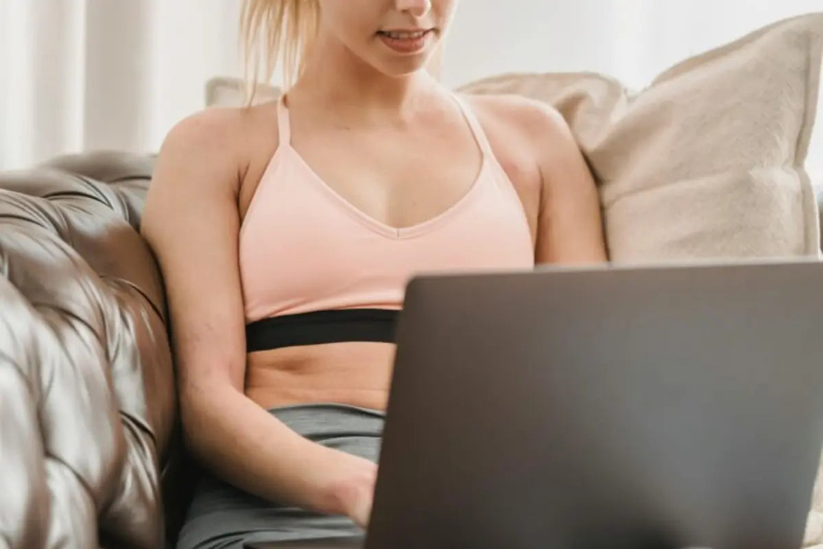 Seamless bralettes worn by a woman working on a laptop while lounging comfortably on a leather couch.