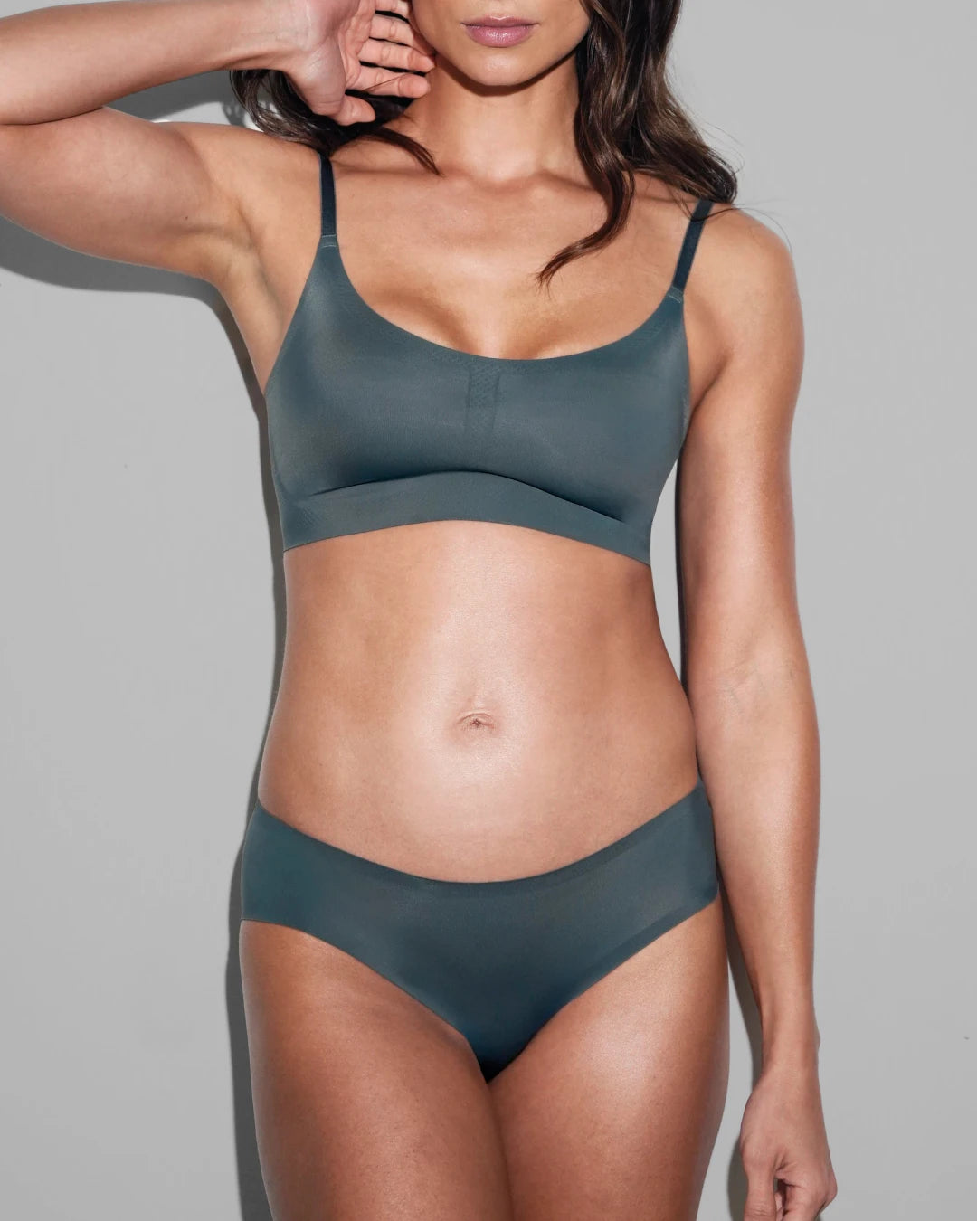  Model wearing a matching slate blue seamless scoop-neck bralette and bikini brief set.