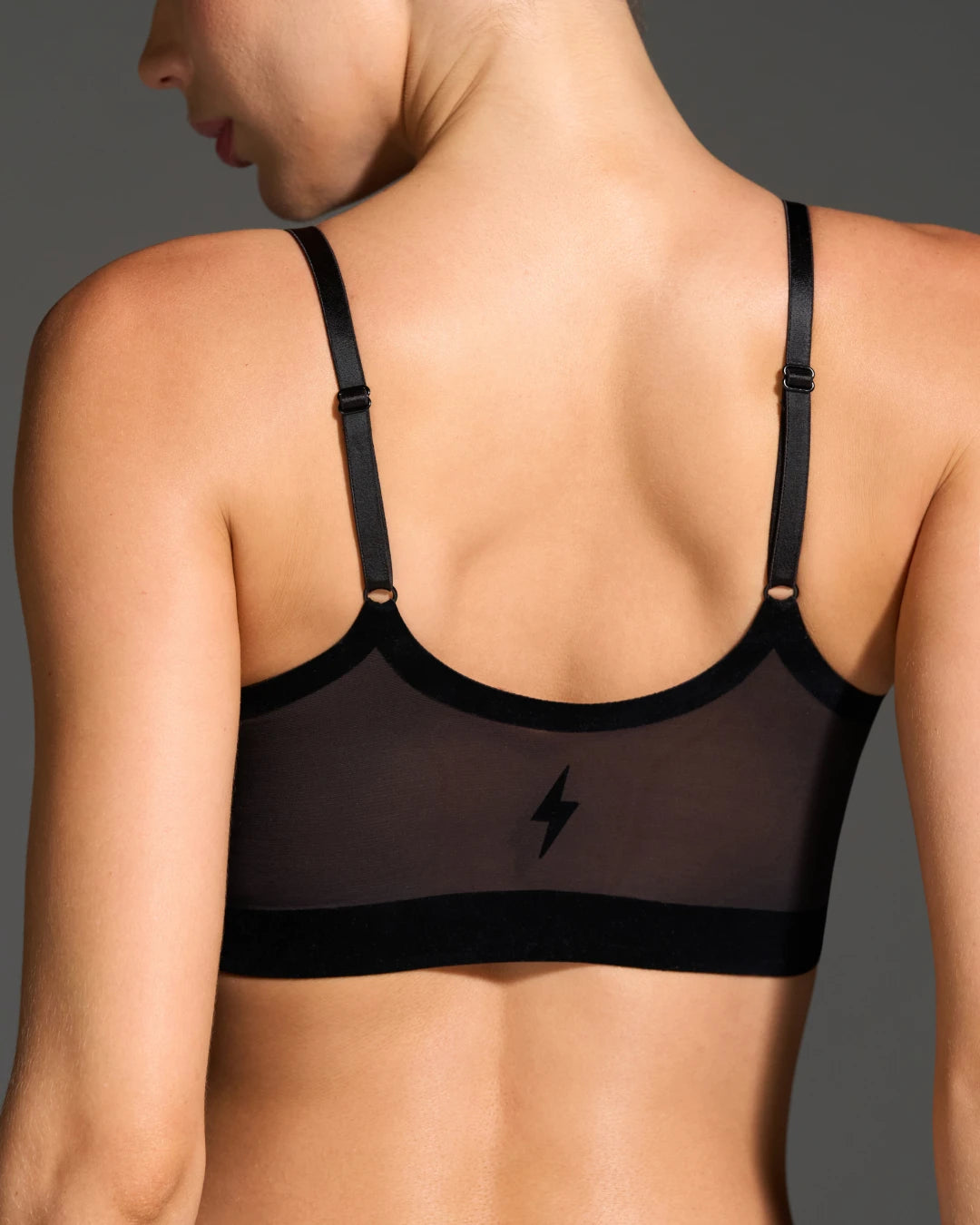 Seamless wireless bralette in black with mesh back panel and adjustable straps modeled from behind