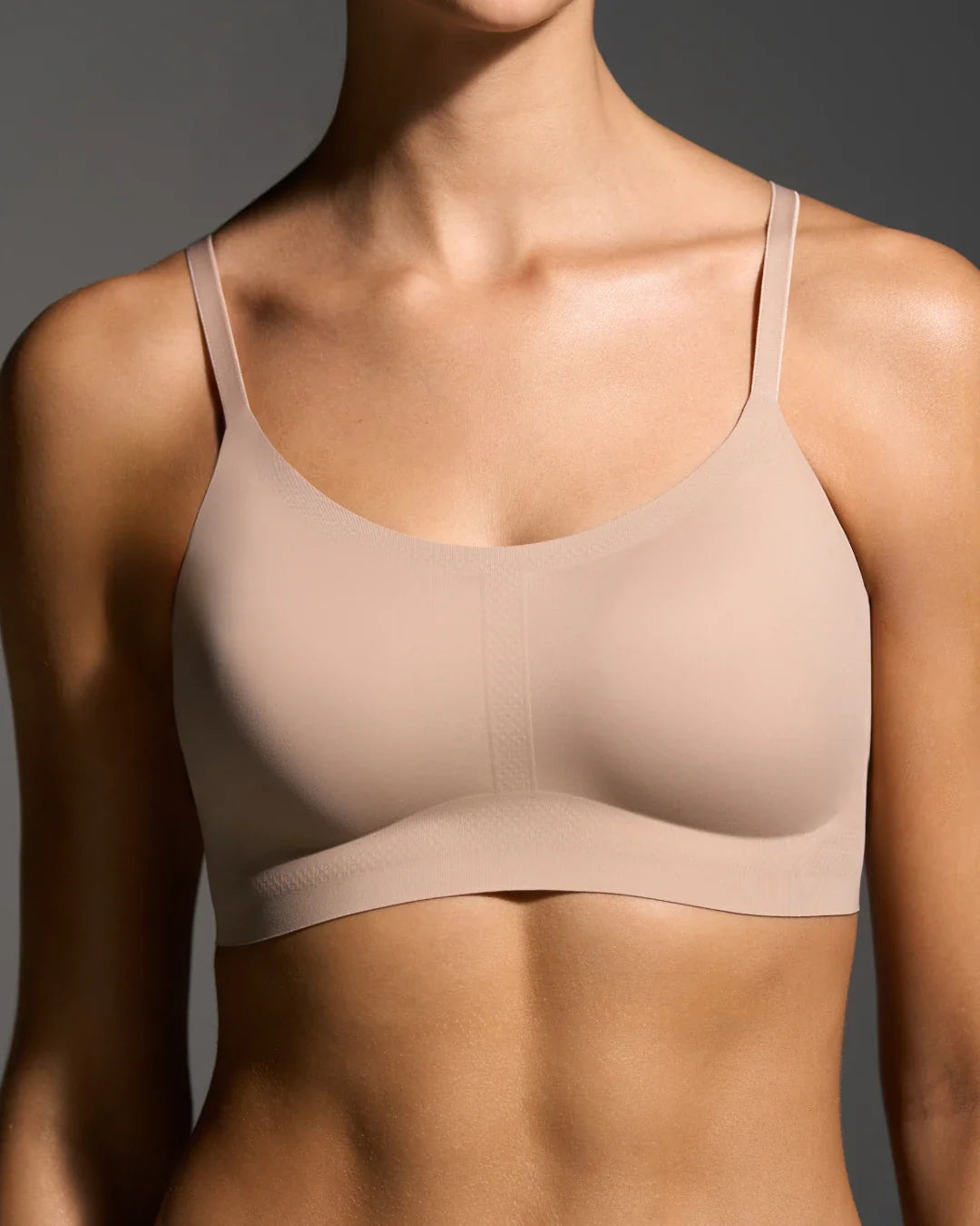 Three nude support bralettes in a cascading flat-lay arrangement.