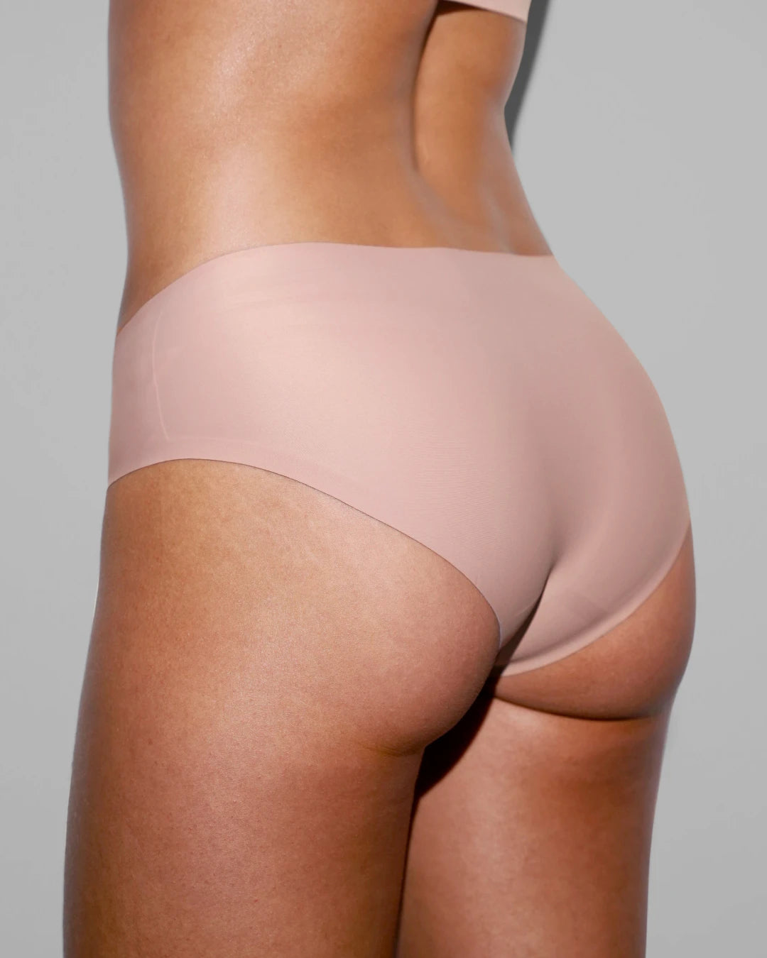 Back view of blush pink seamless hipster briefs showing the smooth bonded edges and moderate coverage fit.